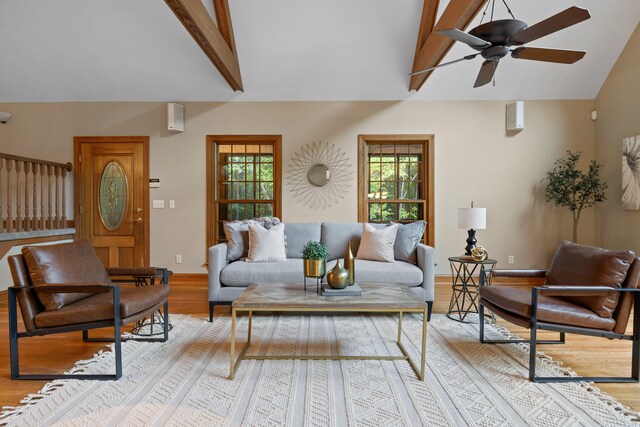 living room featuring light hardwood / wood-style flooring, beamed ceiling, high vaulted ceiling, and ceiling fan