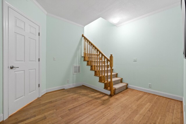 stairway featuring ornamental molding, hardwood / wood-style floors, and a textured ceiling