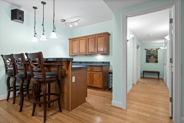 kitchen featuring light hardwood / wood-style flooring, a kitchen bar, and decorative light fixtures