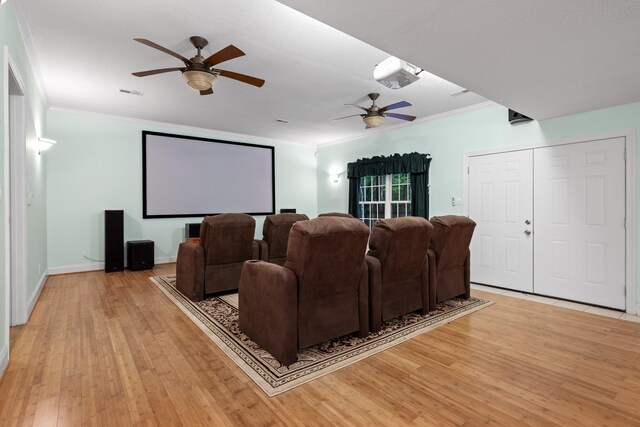 cinema room with ceiling fan, crown molding, and light hardwood / wood-style flooring