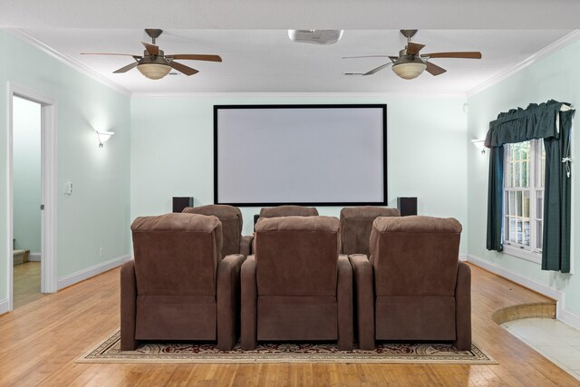 home theater room featuring crown molding, light wood-type flooring, and ceiling fan