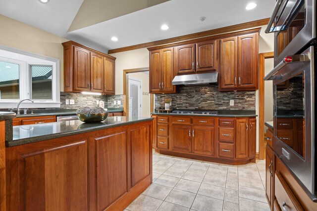 kitchen with sink, decorative backsplash, light tile patterned flooring, and dark stone countertops