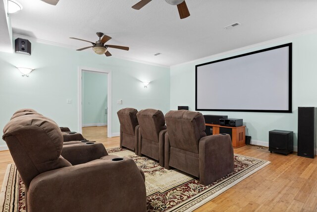 home theater room featuring light hardwood / wood-style flooring, crown molding, and ceiling fan