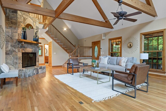 living room with beam ceiling, light hardwood / wood-style floors, a fireplace, and high vaulted ceiling