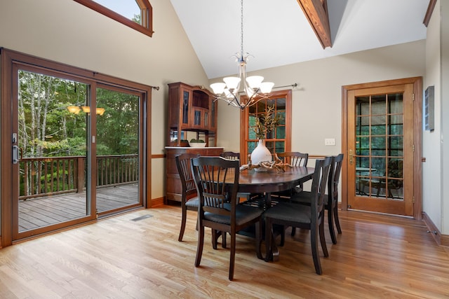 dining room featuring a wealth of natural light, an inviting chandelier, high vaulted ceiling, and light wood-type flooring