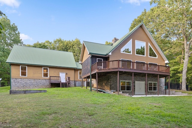 rear view of house featuring a wooden deck, a yard, and stone siding