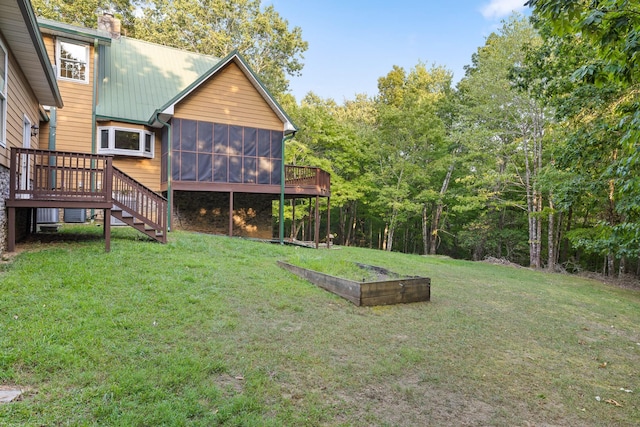 view of yard with stairway, a deck, a garden, and a sunroom