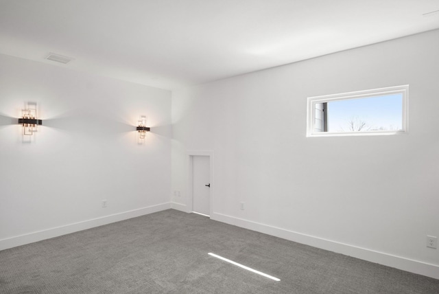 spare room with visible vents, dark carpet, and baseboards