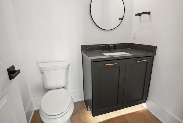 bathroom featuring toilet, baseboards, wood finished floors, and vanity