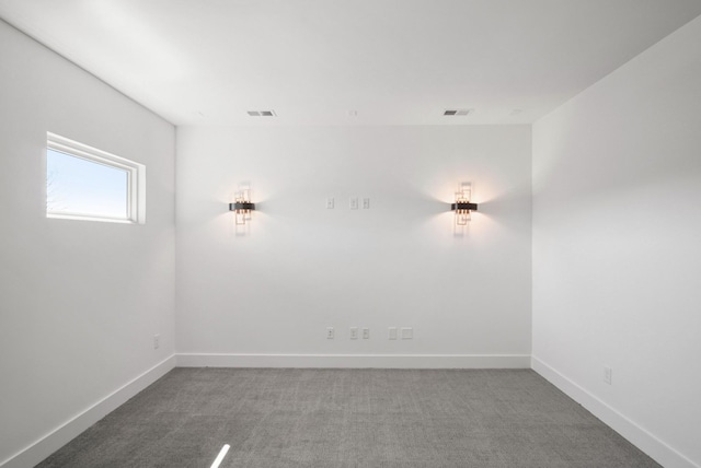 spare room with carpet floors, visible vents, and baseboards