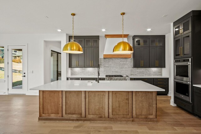 kitchen featuring light wood-type flooring, double oven, light countertops, and a sink