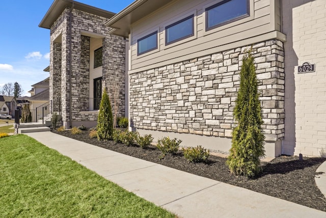 view of property exterior with stone siding and a yard