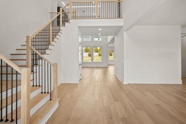 foyer featuring recessed lighting, a high ceiling, wood finished floors, baseboards, and stairs