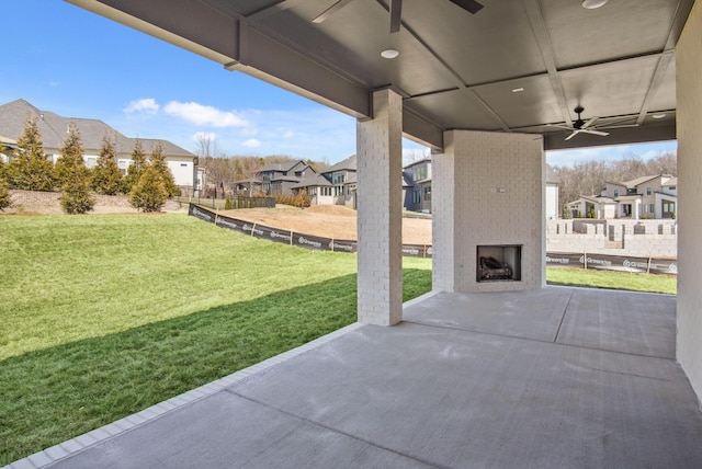 view of patio with an outdoor brick fireplace, a residential view, fence, and ceiling fan