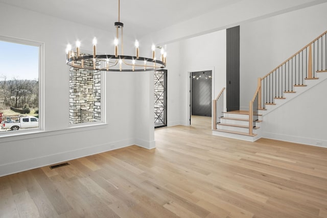 unfurnished dining area featuring baseboards, stairs, visible vents, and wood finished floors