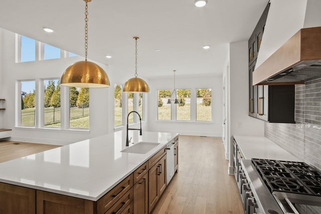 kitchen with wall chimney exhaust hood, backsplash, a sink, and a wealth of natural light