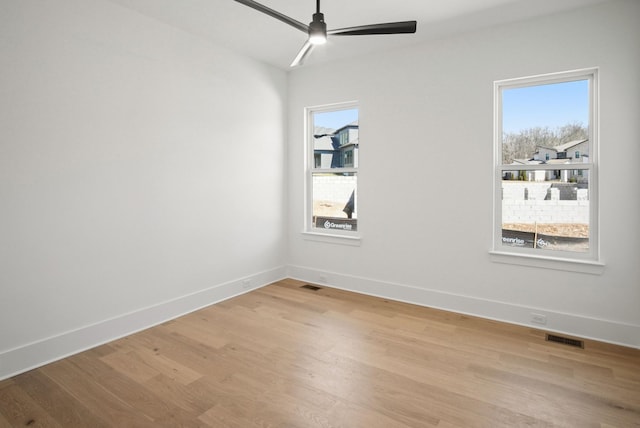 unfurnished room featuring a healthy amount of sunlight, light wood finished floors, ceiling fan, and visible vents