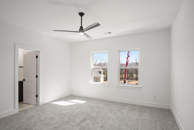 carpeted spare room featuring baseboards, visible vents, and a ceiling fan