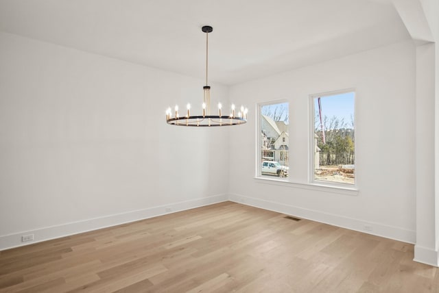 unfurnished dining area featuring light wood-type flooring, an inviting chandelier, baseboards, and visible vents