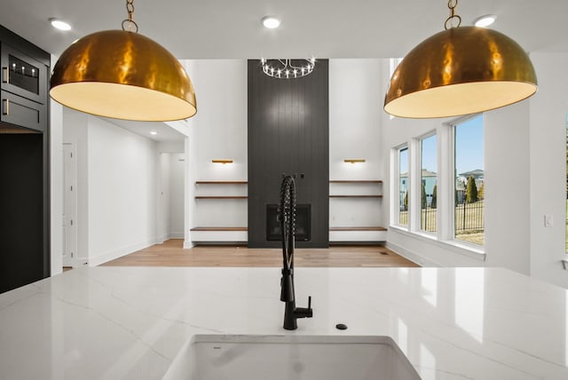 interior space featuring light stone counters, recessed lighting, a sink, and pendant lighting