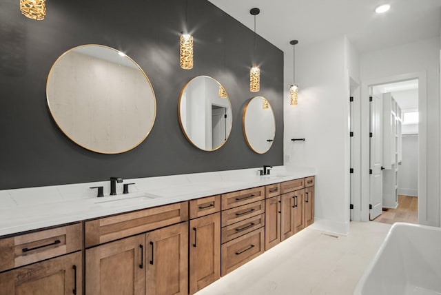 bathroom with a freestanding tub, a sink, baseboards, and double vanity