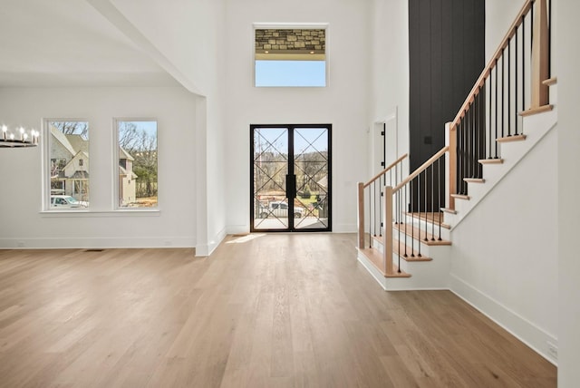 foyer with baseboards, a notable chandelier, stairway, and wood finished floors