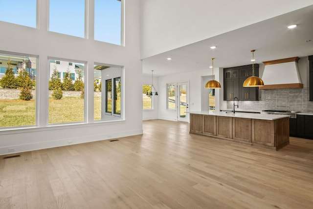 kitchen featuring light wood finished floors, visible vents, open floor plan, light countertops, and premium range hood