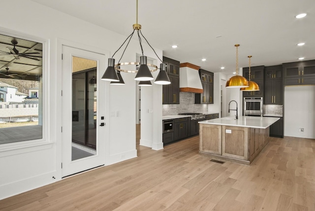 kitchen with premium range hood, light countertops, appliances with stainless steel finishes, light wood-type flooring, and decorative backsplash