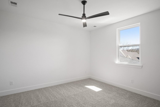 carpeted spare room featuring ceiling fan, visible vents, and baseboards