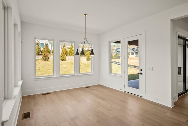 unfurnished dining area featuring wood finished floors, visible vents, and baseboards