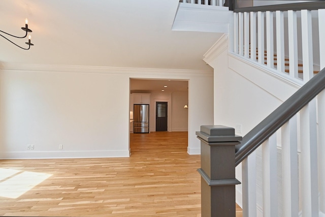 interior space with stairway, light wood-style flooring, baseboards, and ornamental molding