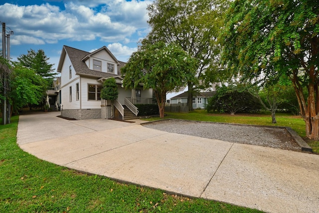 view of front of house featuring a front yard, concrete driveway, and roof with shingles