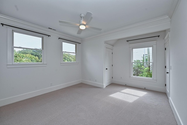 spare room with light carpet, visible vents, a wealth of natural light, and ornamental molding