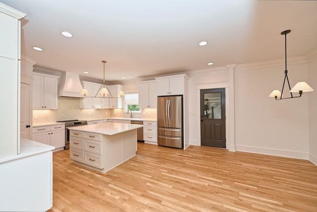 kitchen featuring light wood finished floors, premium range hood, an inviting chandelier, stainless steel appliances, and a sink