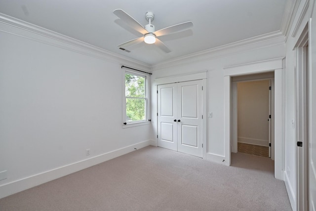 unfurnished bedroom with a closet, light colored carpet, crown molding, and baseboards