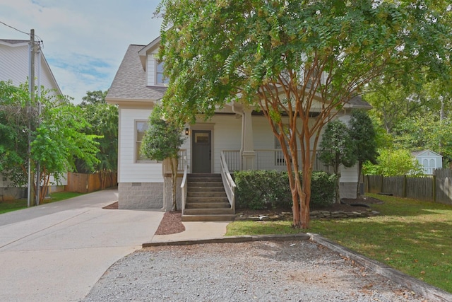 view of front of home with a shingled roof, fence, a front yard, covered porch, and crawl space