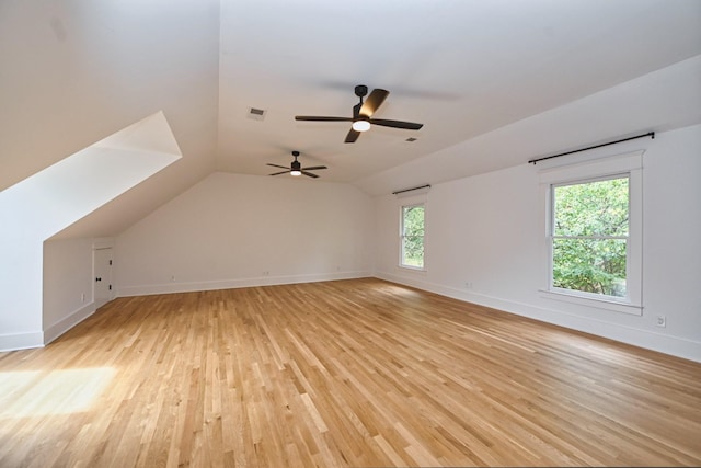 additional living space featuring light wood finished floors, visible vents, baseboards, and lofted ceiling