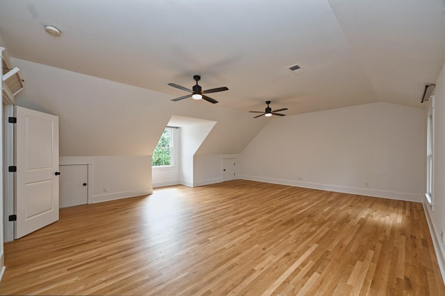 additional living space featuring visible vents, light wood-type flooring, baseboards, and vaulted ceiling