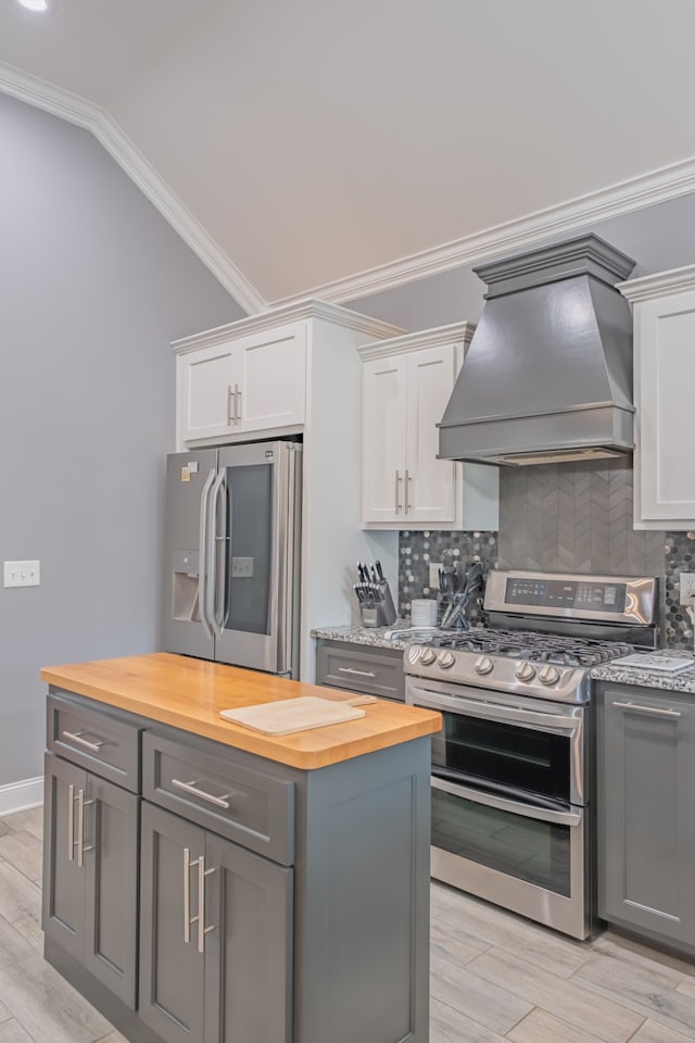 kitchen featuring white cabinets, butcher block counters, appliances with stainless steel finishes, and custom exhaust hood