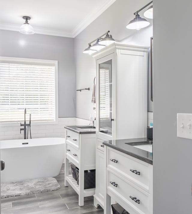 bathroom with vanity, crown molding, hardwood / wood-style flooring, and a tub