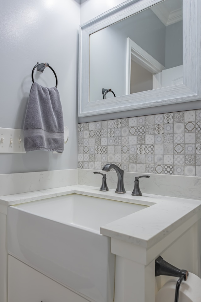 bathroom featuring crown molding, sink, and tasteful backsplash