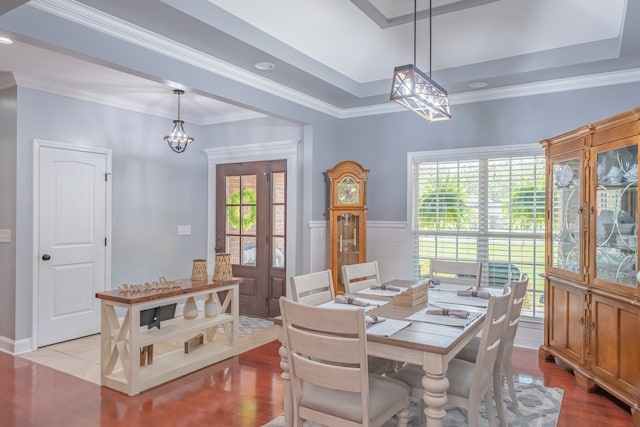 dining space featuring ornamental molding, a chandelier, light hardwood / wood-style floors, and a raised ceiling