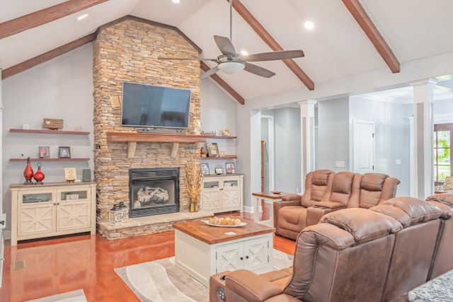 living room with ceiling fan, a stone fireplace, light wood-type flooring, and decorative columns