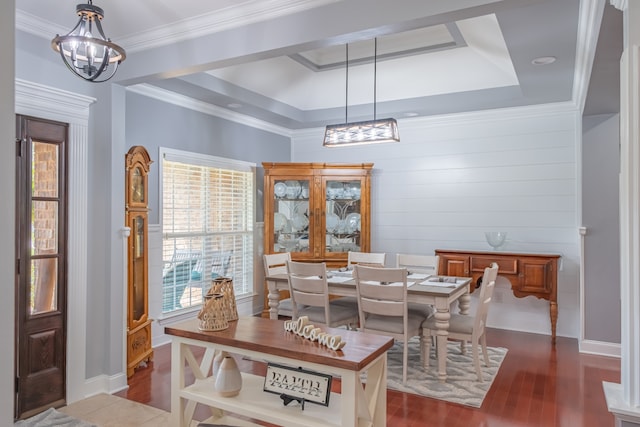 dining area featuring wood walls, ornamental molding, a chandelier, dark wood-type flooring, and a tray ceiling