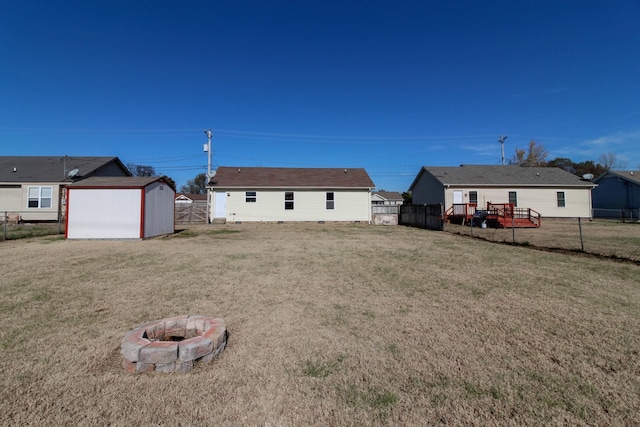 rear view of house with a lawn, an outdoor fire pit, a shed, a fenced backyard, and an outdoor structure