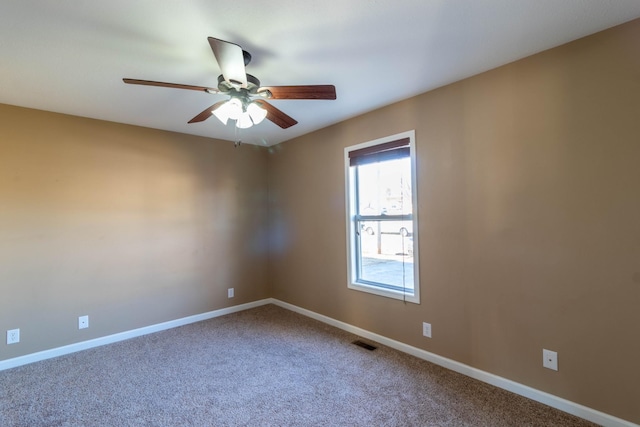 carpeted spare room featuring a ceiling fan, visible vents, and baseboards