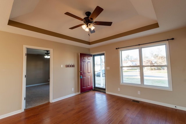 entryway featuring wood finished floors, a raised ceiling, visible vents, and baseboards