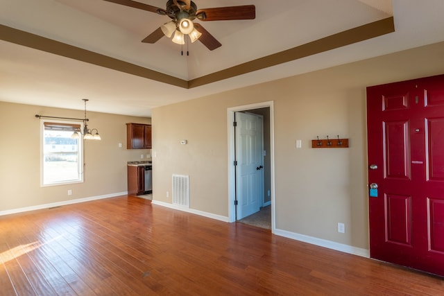 unfurnished living room with ceiling fan with notable chandelier and hardwood / wood-style flooring