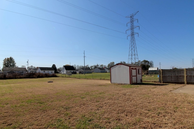 view of yard with an outdoor structure, fence, and a storage shed