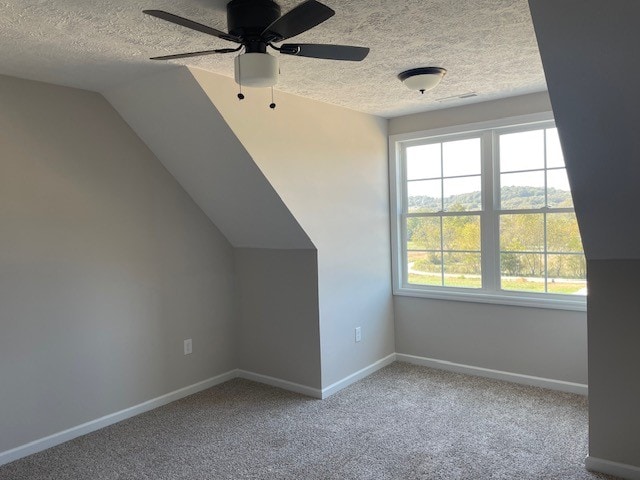 bonus room featuring a textured ceiling, light colored carpet, and vaulted ceiling